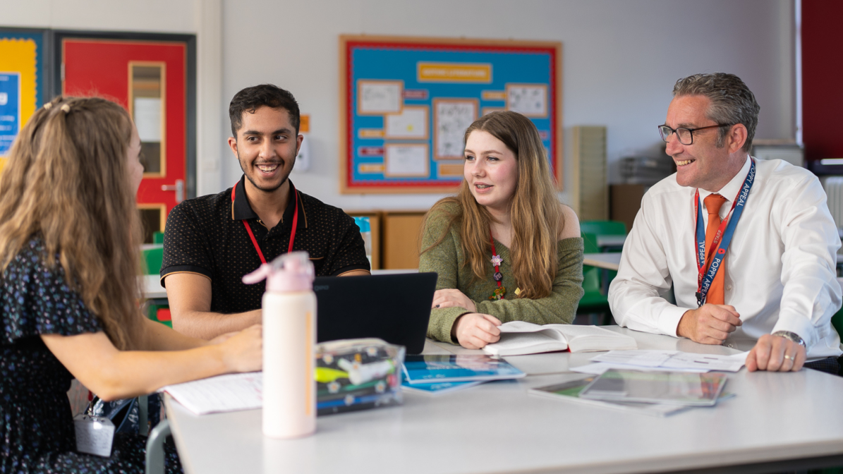 A group of students sat talking to their adviser in a classroom
