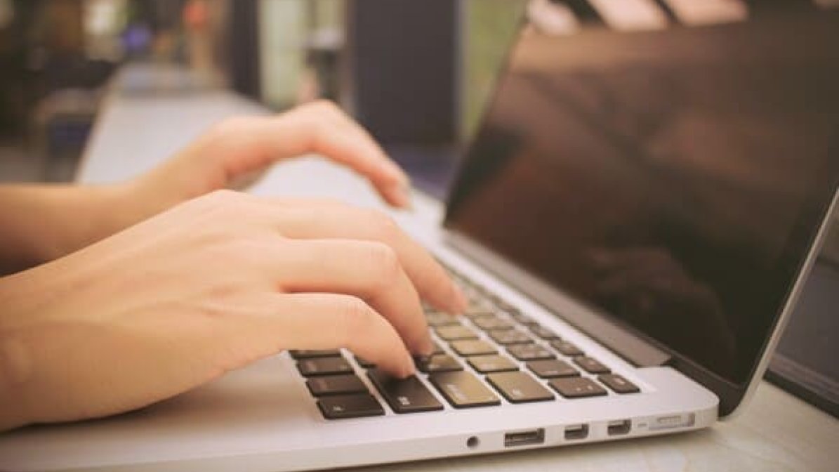 Person's hand typing on laptop 