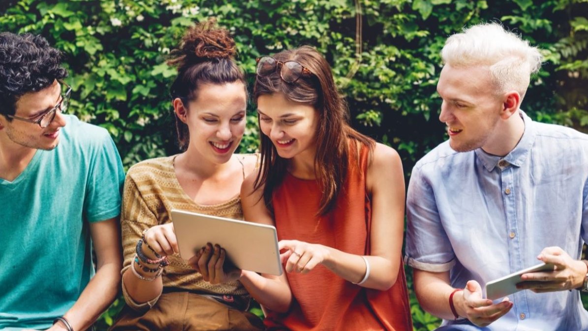 Students sitting on bench engagng with social media on mobile devices 