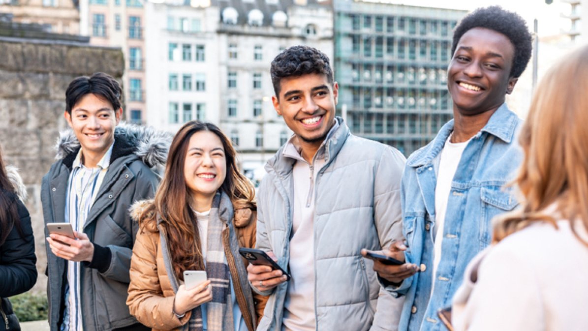 Smiling students on campus with mobile phones