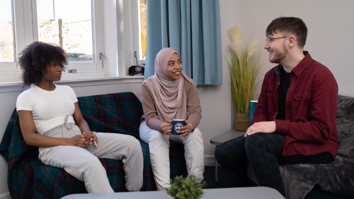 A group of three students sat talking in student accommodation