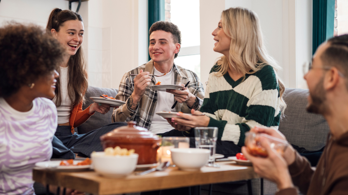 A cheerful group of students enjoying a meal together, sharing laughter and food around a table.