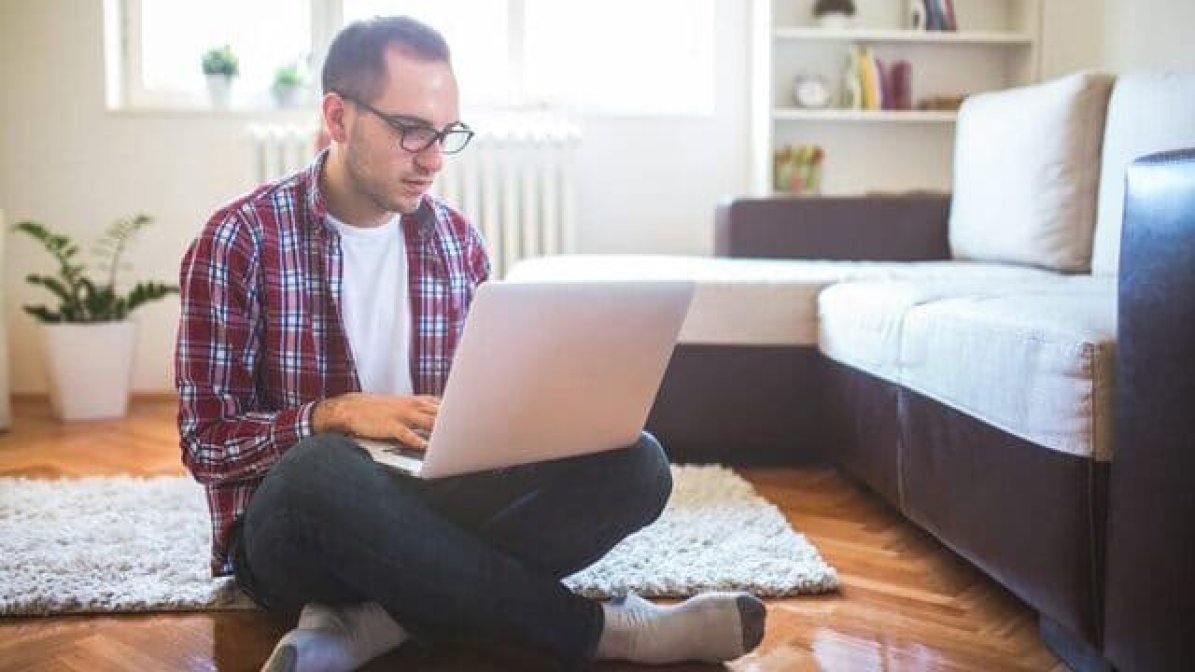 Care experienced student sitting on floor using laptop