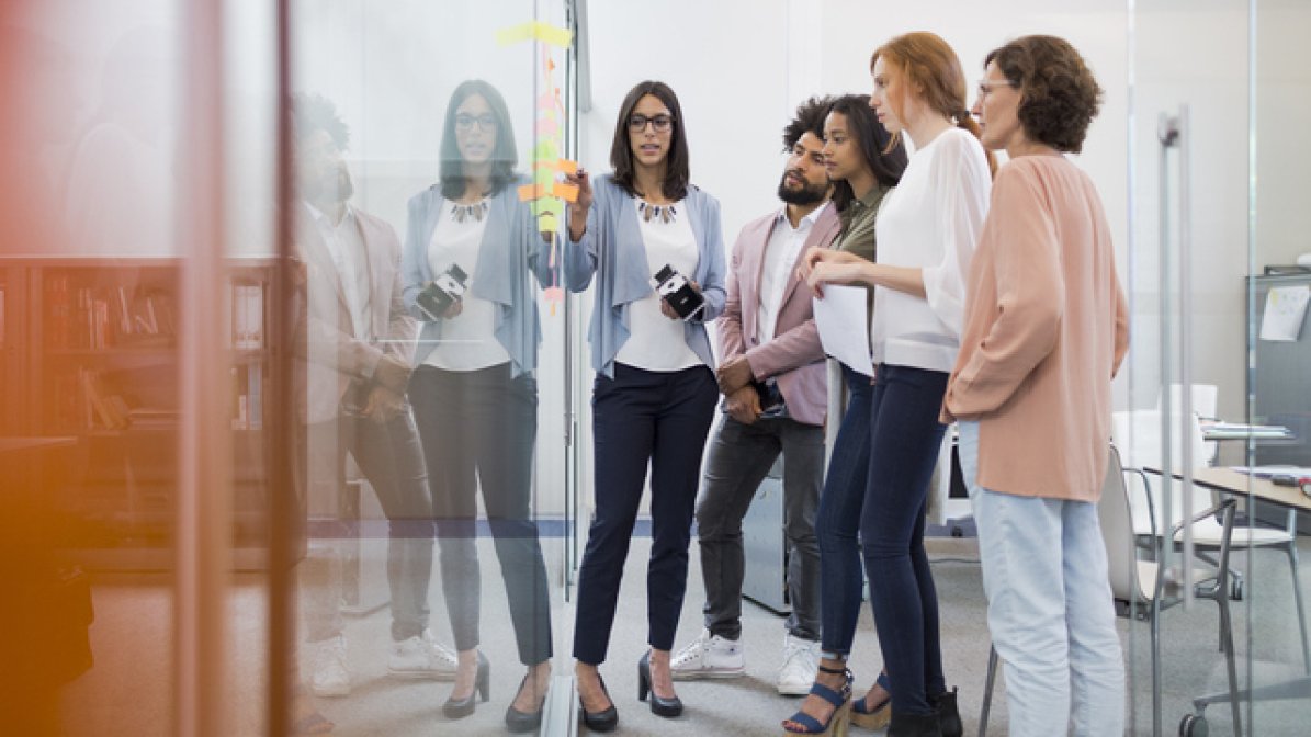 Corporate Innovation Specialist working on whiteboard with a team