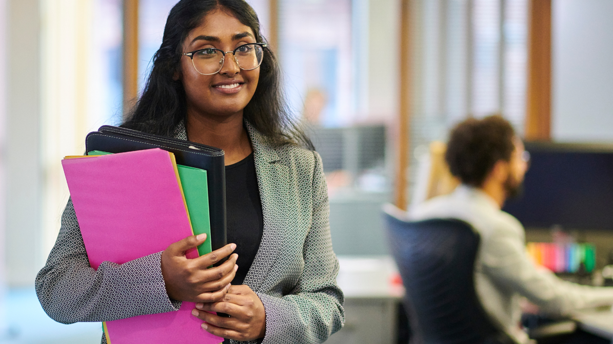 A office worker pictured working through an office carrying notes