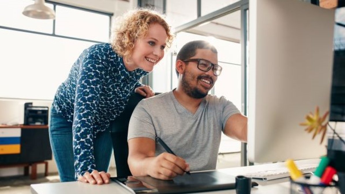 Disabled student using computer with assistant