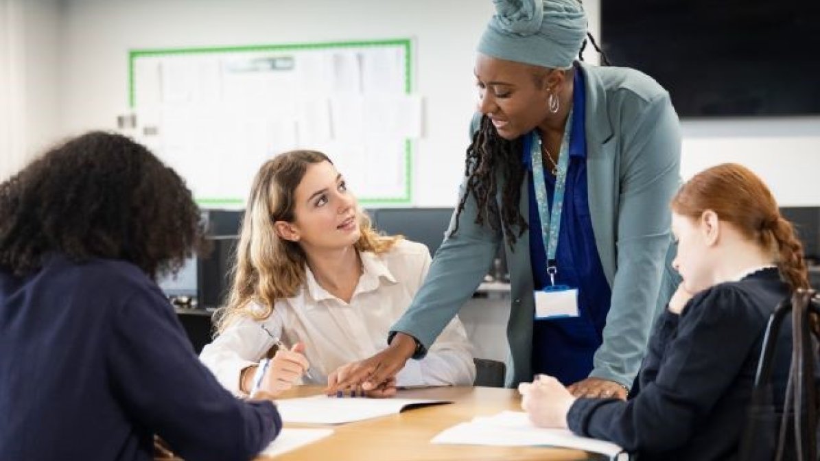 Students with teacher working at desk