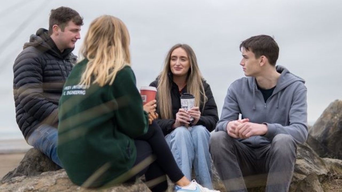 Group of students sitting on beach 