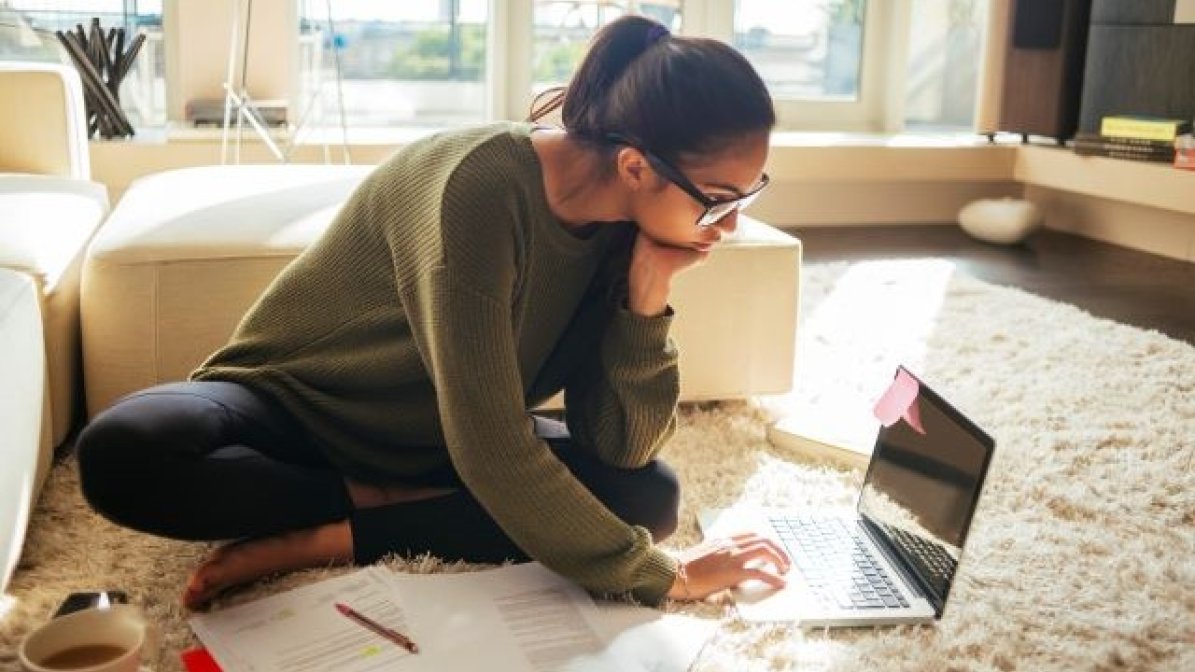 Student sitting on floor writing on laptop