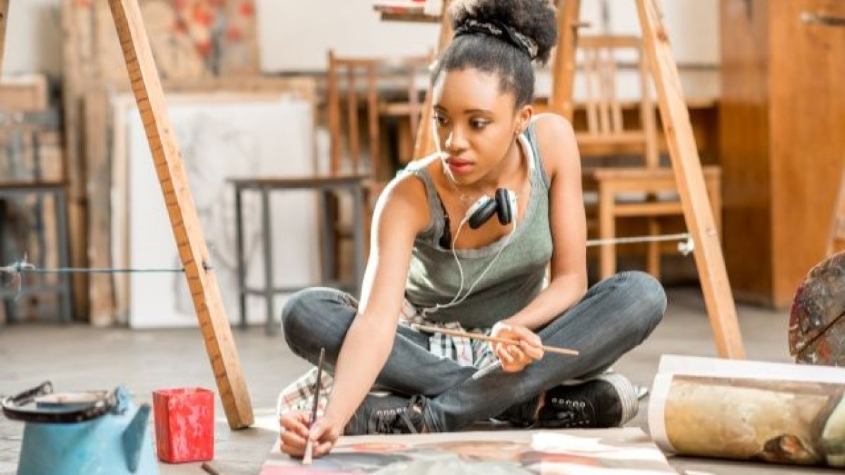 Student sitting on floor painting