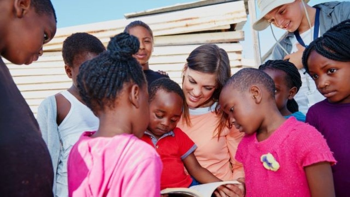 Student volunteer on a gap year reading to students