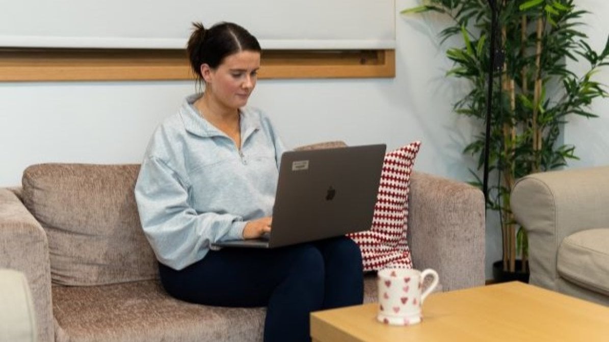 Student sitting on sofa writing on laptop  