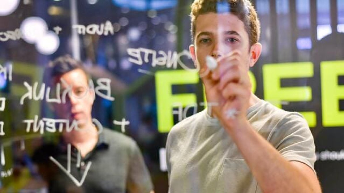 Marketing apprentice writing on board at work