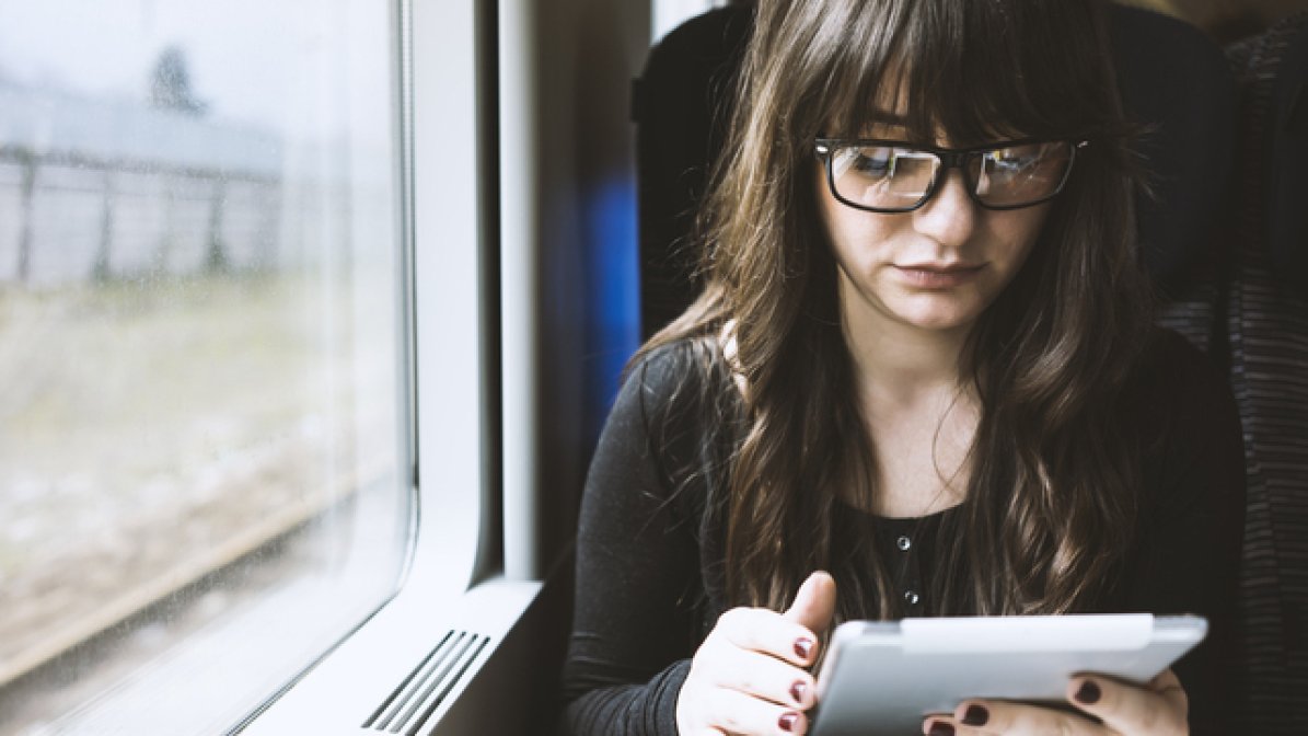 Student looking at tablet on train