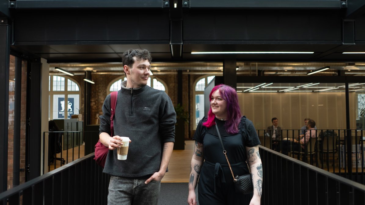 Students walking over a bridge with a coffee