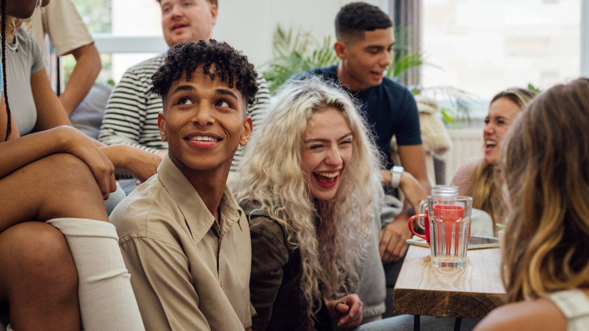 A diverse group of young people sat talking and laughing