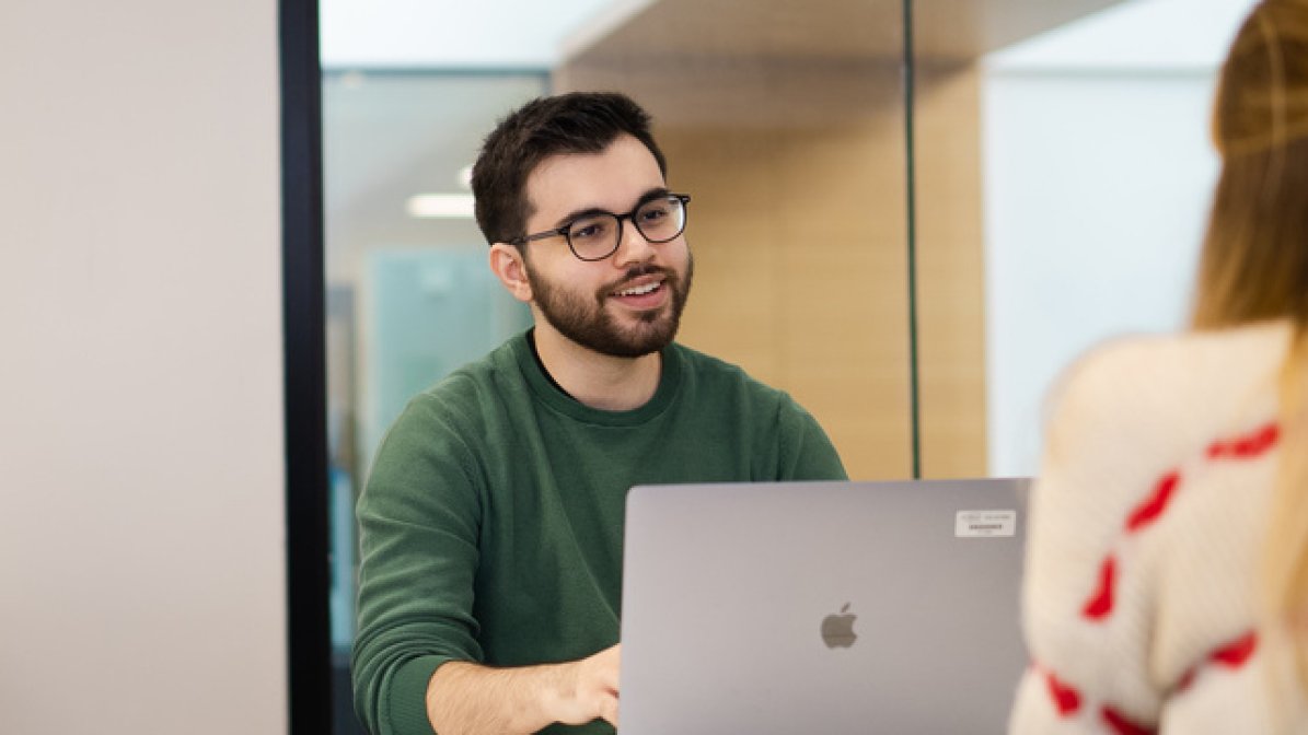 Student using laptop with adviser 