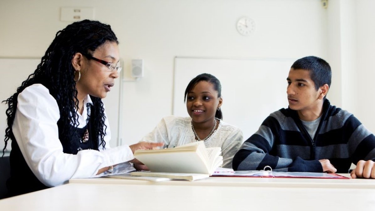 Adviser talking to students at desk 