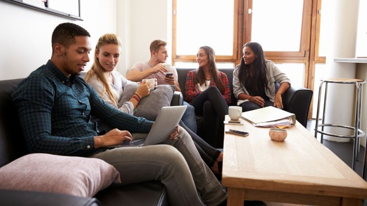 Students in accommodation communal area searching for scholarships