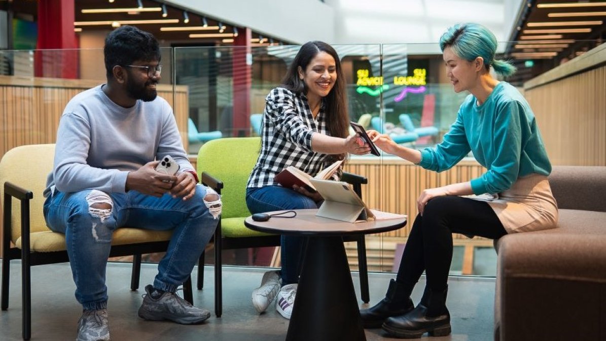 Students looking at mobile phone in communal area at university