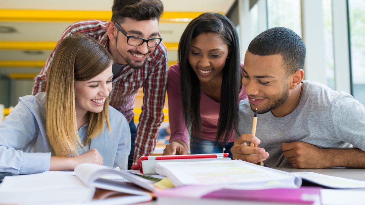 Apprentices studying around a desk 