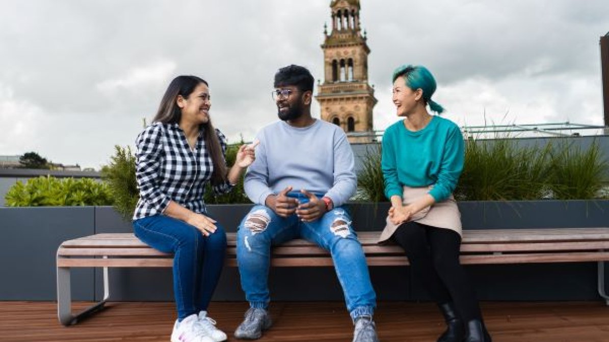 Students chatting on a bench in front of city landmark