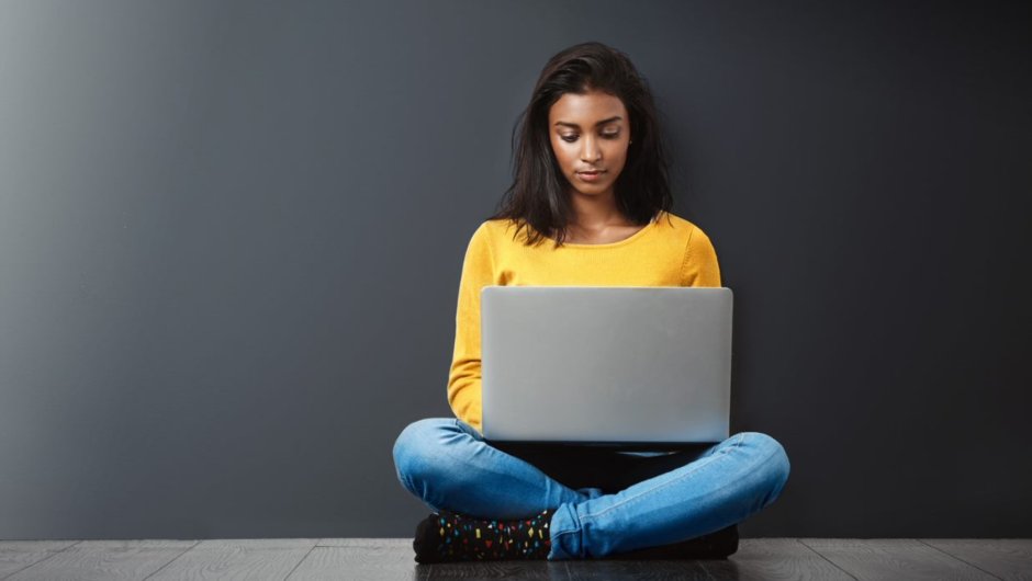 A young woman sits at a laptop