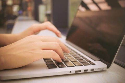 Person's hand typing on laptop 