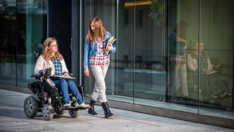 Student in wheelchair and student walking on campus