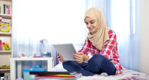 Student sitting on bed chatting online to students using Unibuddy 