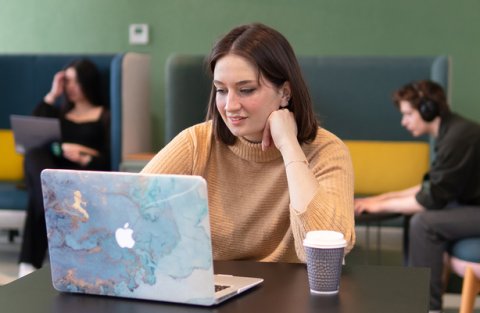 Student using laptop in communal area at university