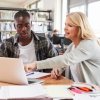 Student with adviser in library looking at laptop